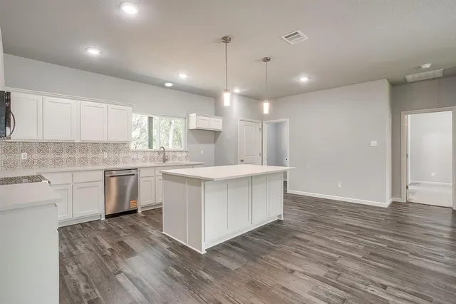 a large kitchen with granite countertop a white stove top oven and white cabinets