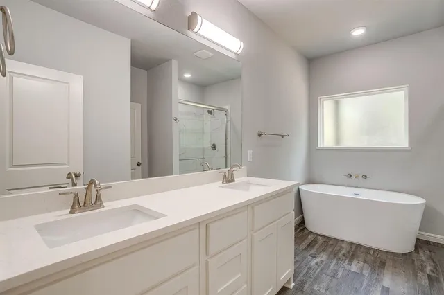 a bathroom with a double vanity sink mirror and bathtub