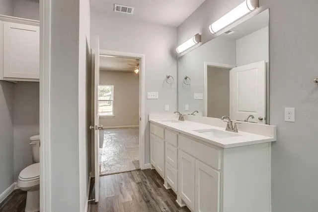 a bathroom with a sink a toilet and a large mirror