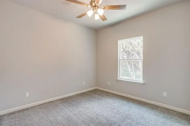 an empty room with a window and a fan