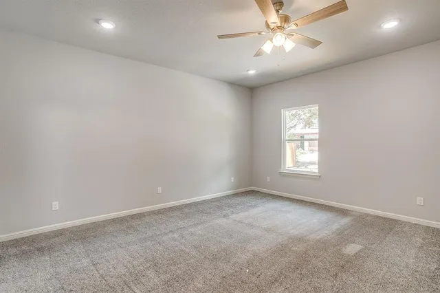 an empty room with a window and a fan