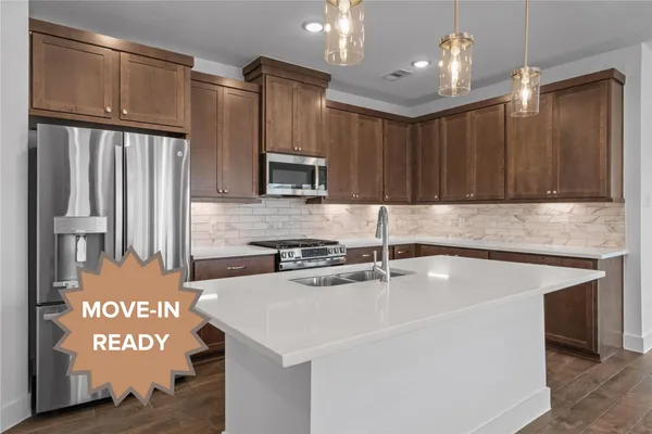 a kitchen with kitchen island granite countertop a sink cabinets and stainless steel appliances