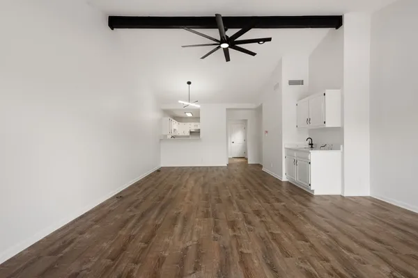 a view of empty room with wooden floor and ceiling fan
