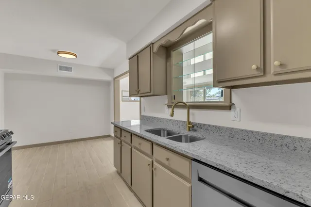 a kitchen with granite countertop a sink and a white cabinets