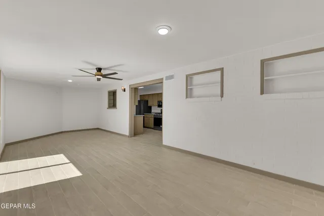 an empty room with a ceiling fan and a rug