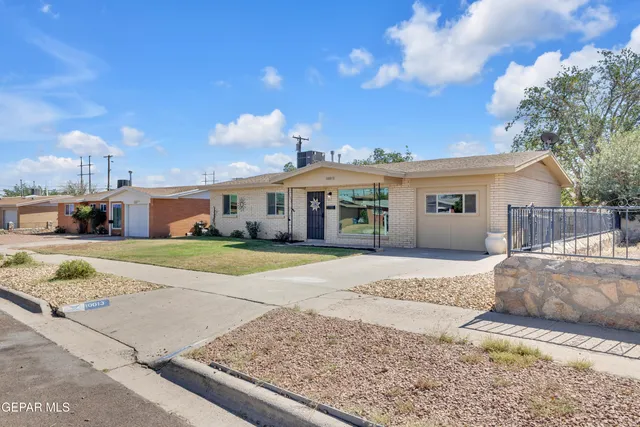 a view of a white house in front of a yard with potted plants