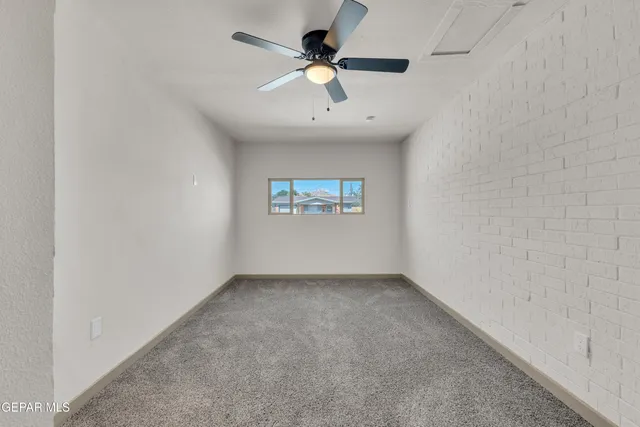 an empty room with a window and a ceiling fan