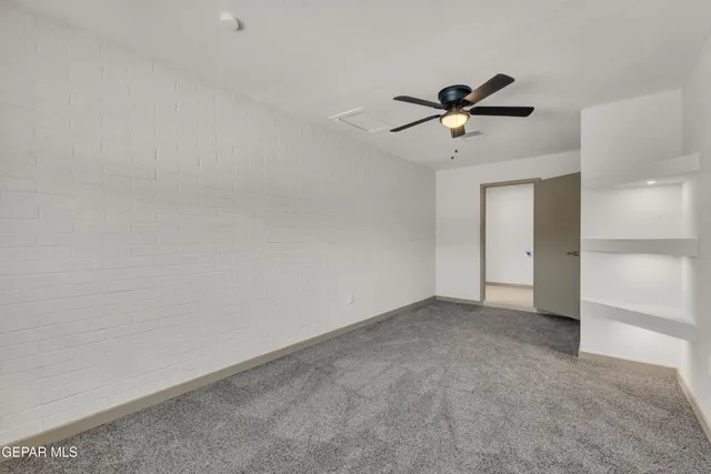 an empty room with a ceiling fan and a window