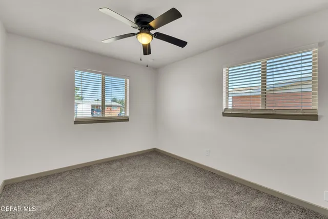 an empty room with a window and a ceiling fan