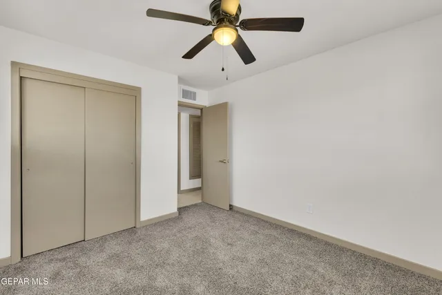 an empty room with closet and a chandelier fan