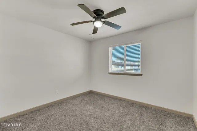 an empty room with a window and a ceiling fan