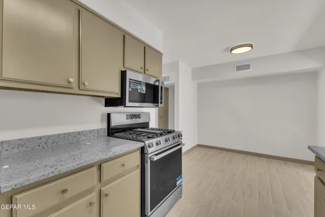 a kitchen with granite countertop a sink a stove and cabinets