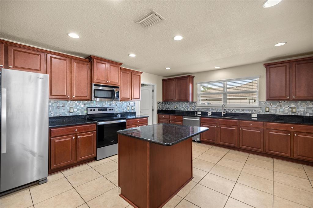 4441 Southwest 62nd Loop Ocala, FL 34474 - Photo 22 of 42 a kitchen with stainless steel appliances granite countertop a stove top oven a sink dishwasher and a refrigerator with wooden cabinets