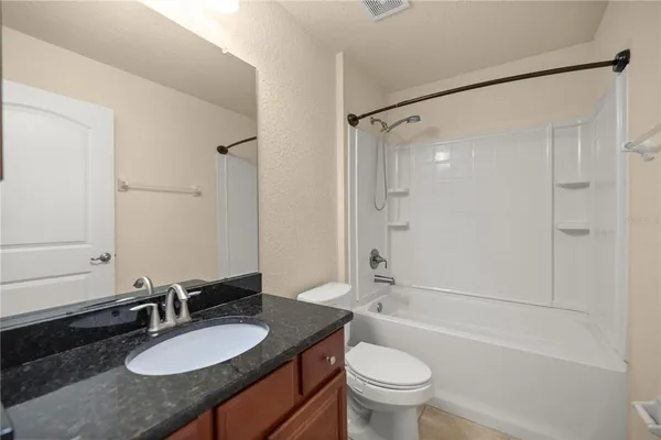 a bathroom with a granite countertop sink toilet mirror and shower