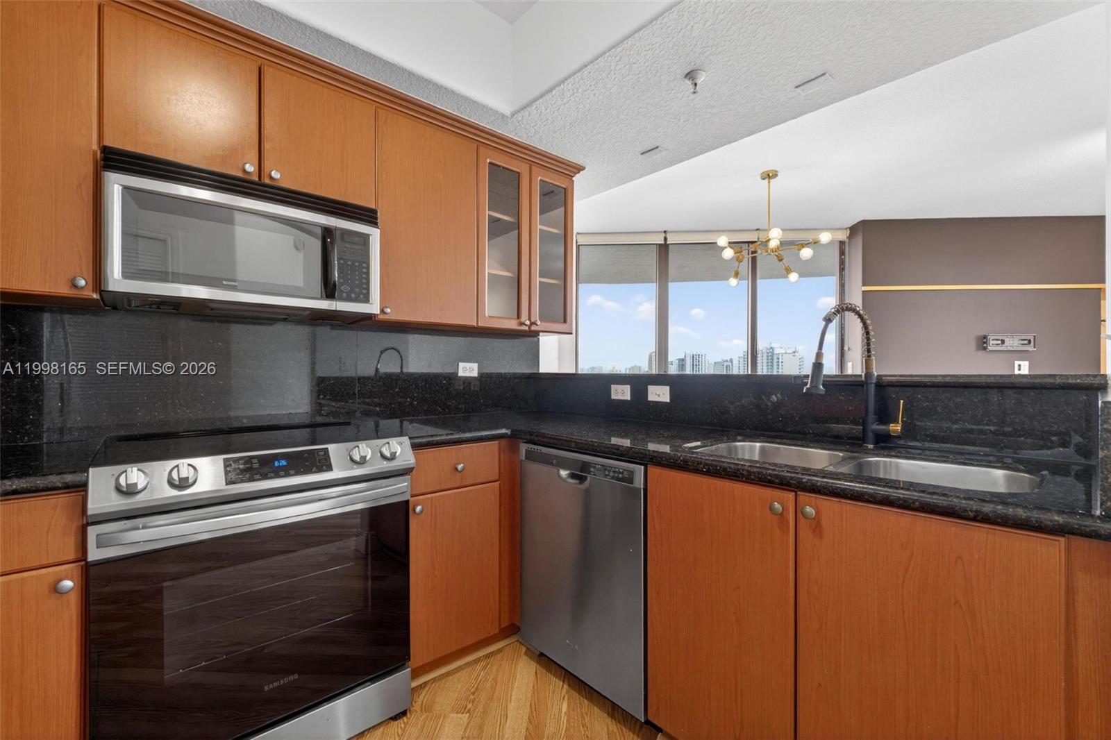 2301 Southwest 27th Avenue, Unit 906 Miami, FL 33145 - Photo 11 of 38 a kitchen with stainless steel appliances granite countertop a stove a sink and a microwave
