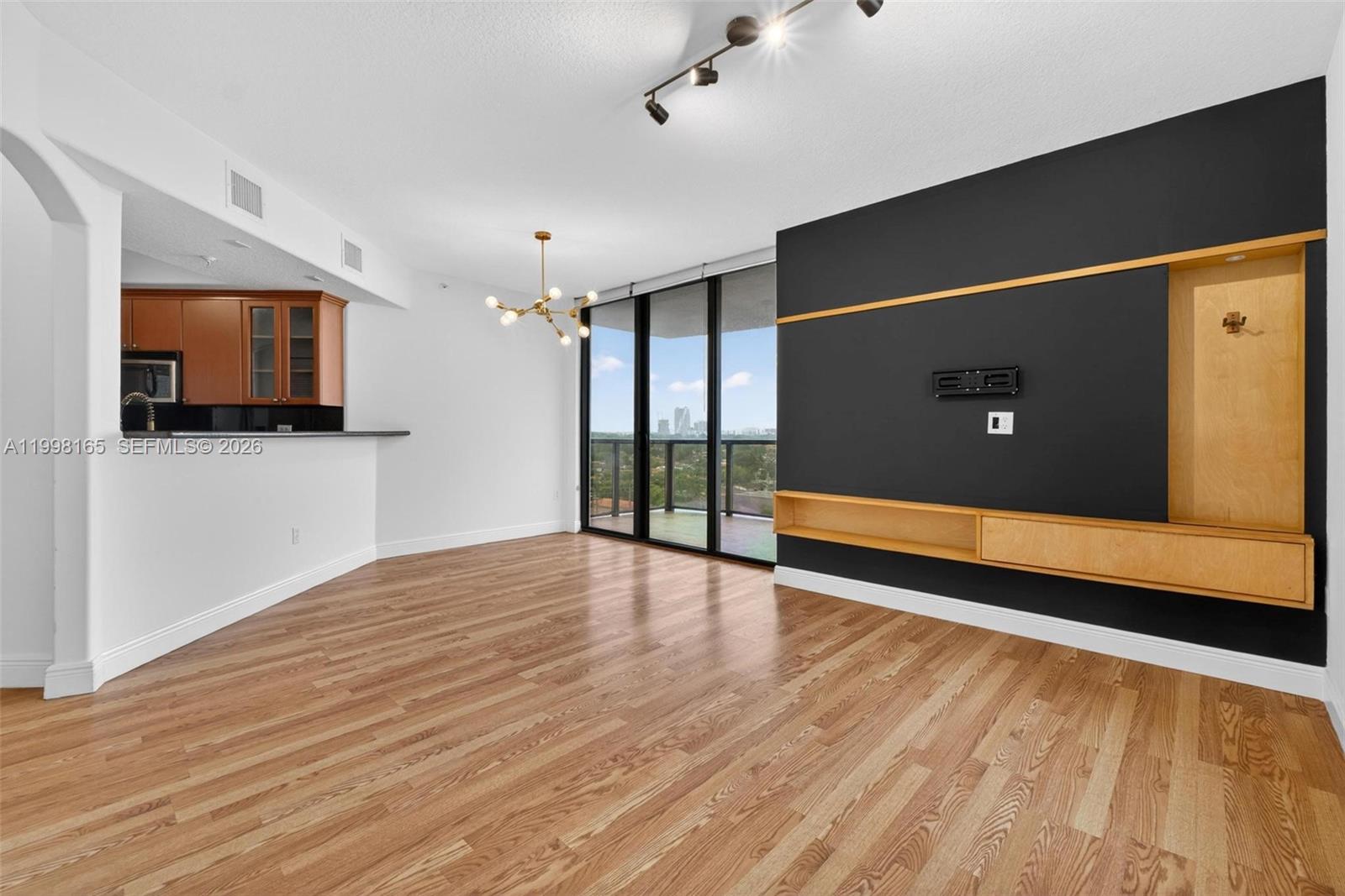 2301 Southwest 27th Avenue, Unit 906 Miami, FL 33145 - Photo 17 of 38 a view of an empty room with wooden floor and a flat screen tv