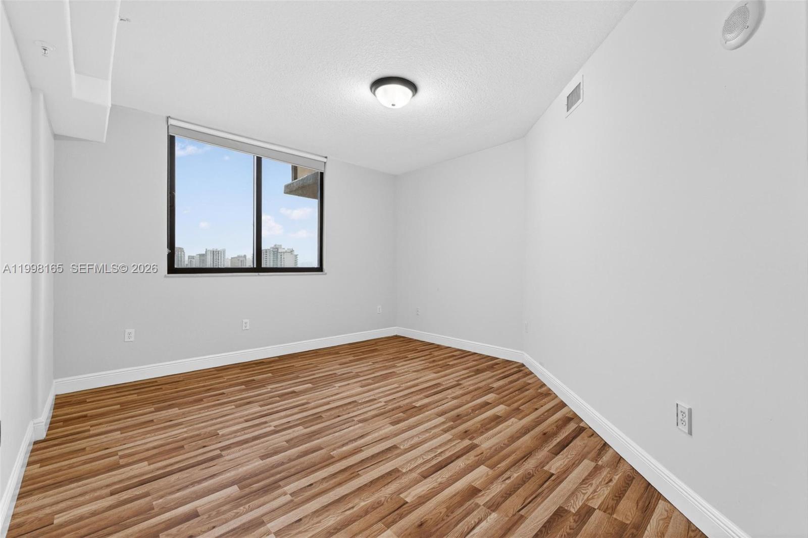 2301 Southwest 27th Avenue, Unit 906 Miami, FL 33145 - Photo 22 of 38 a view of an empty room with wooden floor and a window