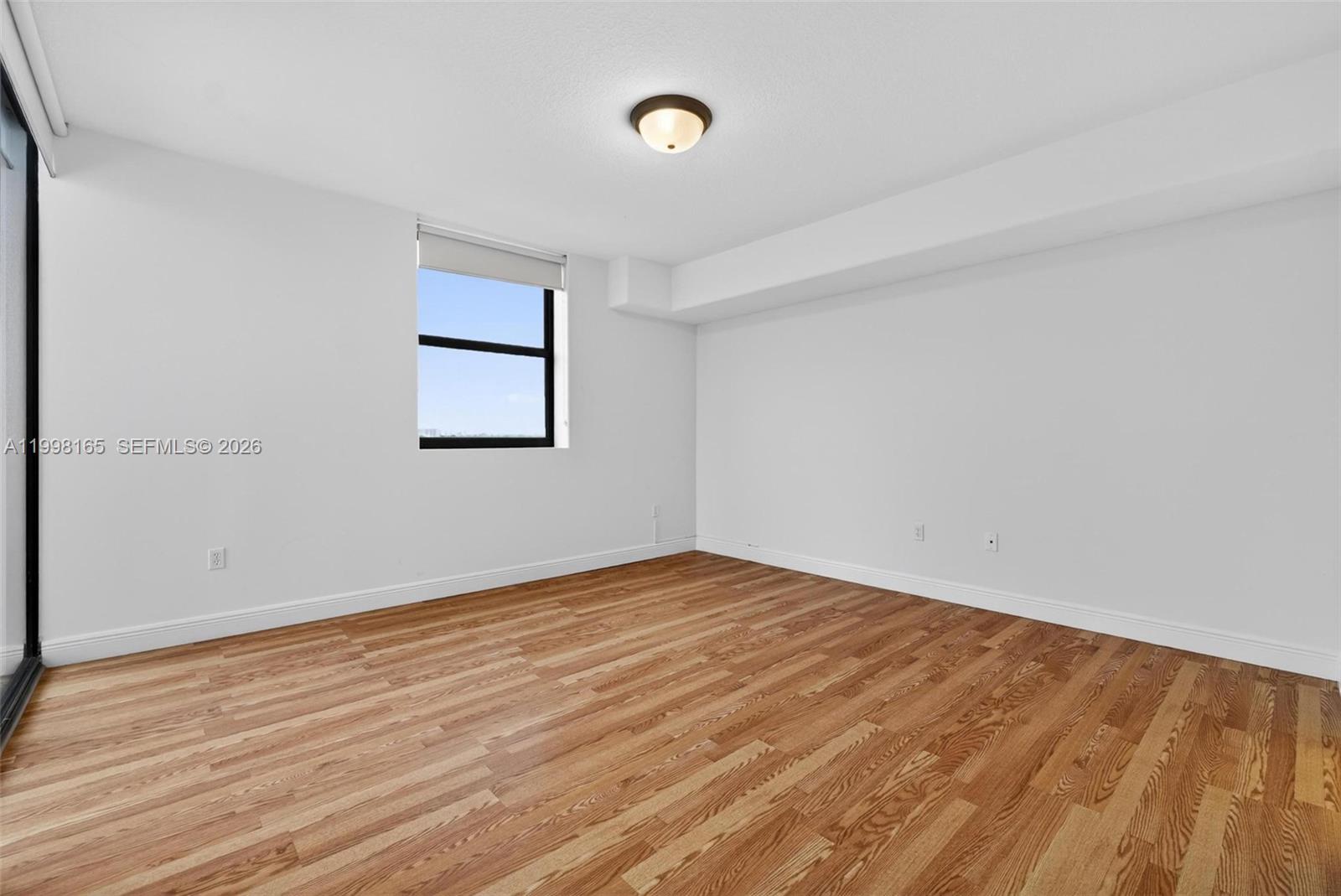 2301 Southwest 27th Avenue, Unit 906 Miami, FL 33145 - Photo 26 of 38 a view of an empty room with wooden floor and a window
