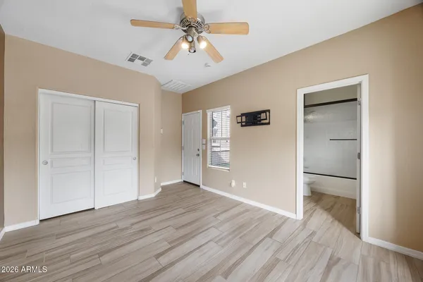a view of an empty room with a window and wooden floor