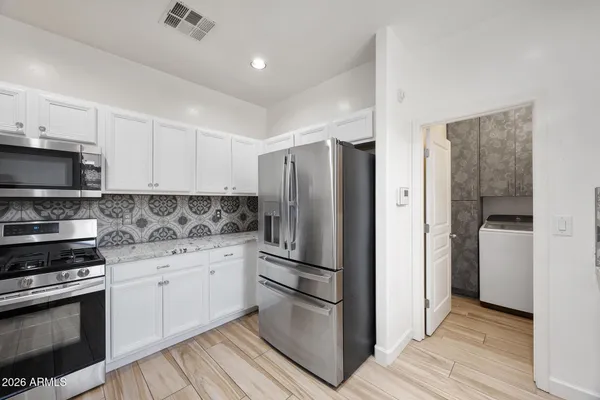 a kitchen with granite countertop white cabinets and stainless steel appliances
