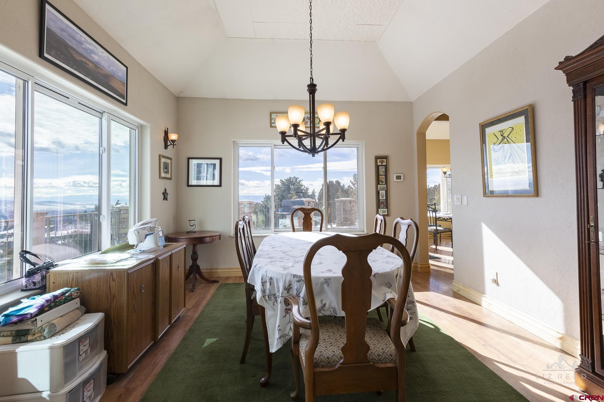 21602 Standingbear Road Cedaredge, CO 81413 - Photo 26 of 35 a view of a dining room with furniture a chandelier and large windows