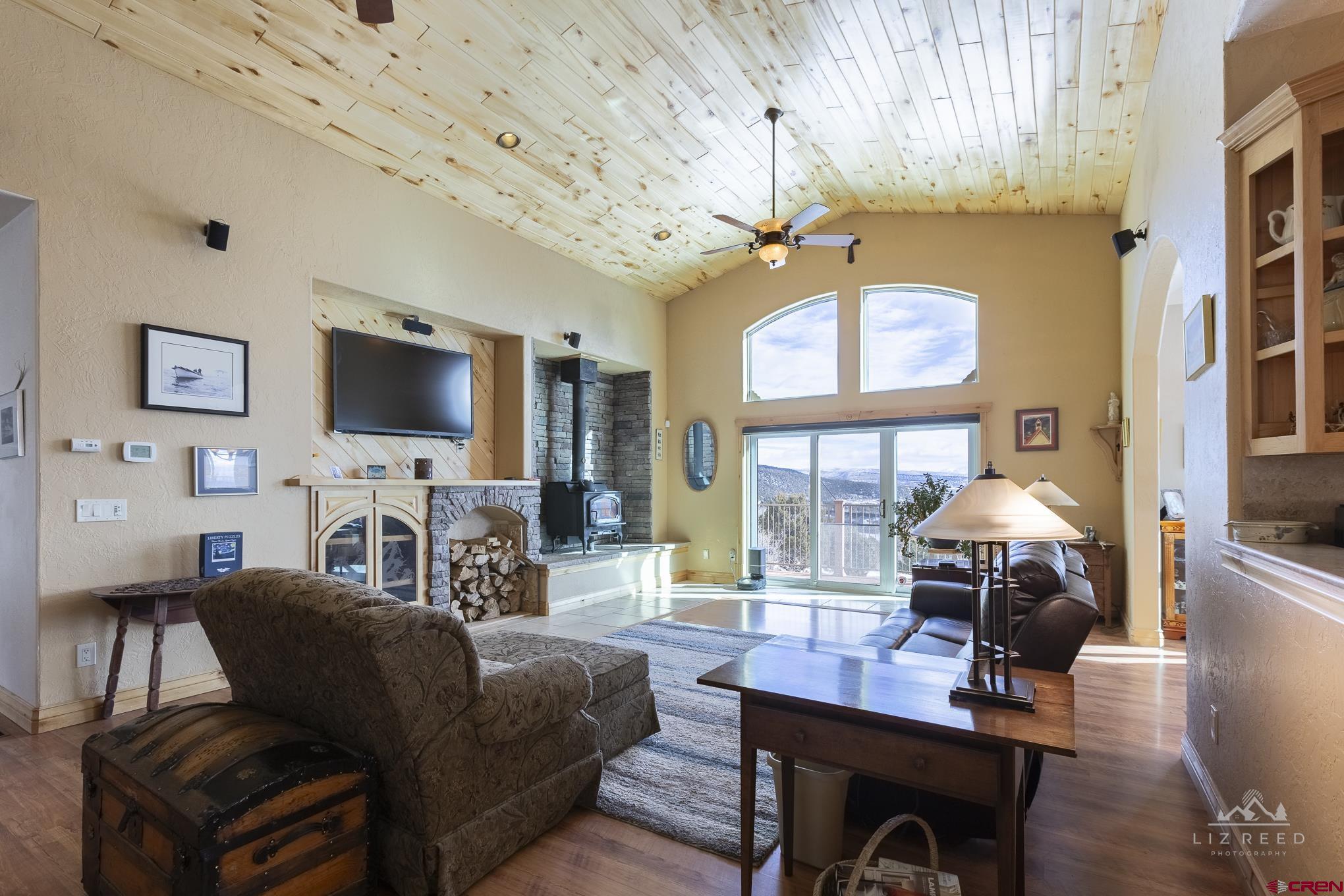 21602 Standingbear Road Cedaredge, CO 81413 - Photo 29 of 35 a living room with furniture a fireplace and a flat screen tv