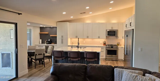a kitchen with stainless steel appliances white cabinets and wooden floor