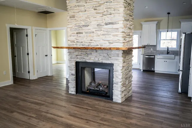 a living room with stainless steel appliances wooden floor and a fireplace
