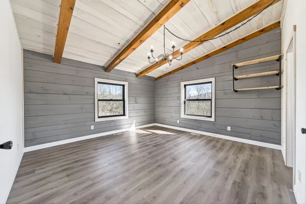 a view of an empty room with a window and wooden floor