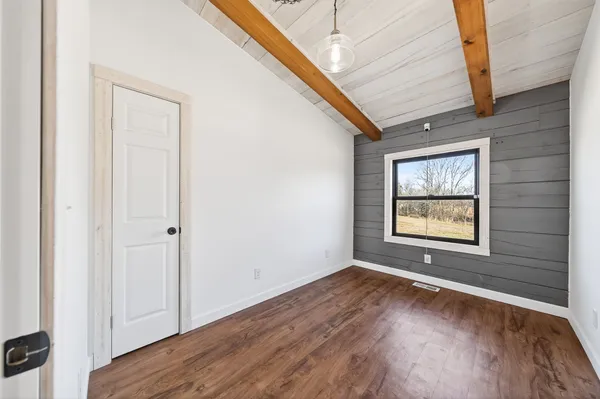 a view of a hallway with wooden floor and a window