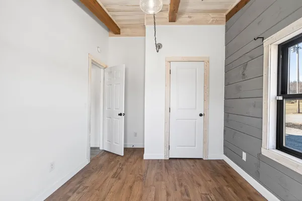 a view of an empty room with wooden floor and cabinet