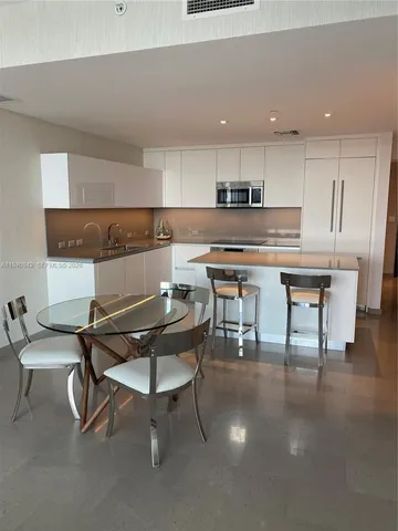 a kitchen with a table chairs a sink dishwasher window and cabinets