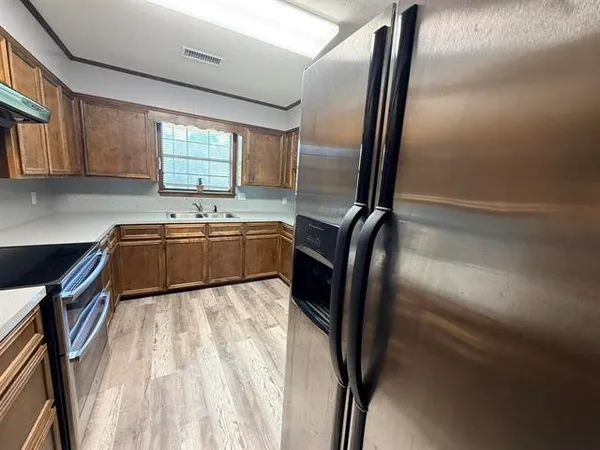 a view of kitchen with stainless steel appliances granite countertop sink refrigerator and window