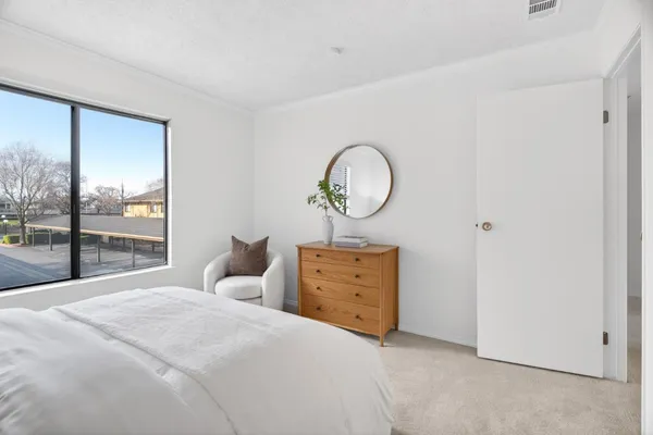 a bedroom with a bed dresser and a large window