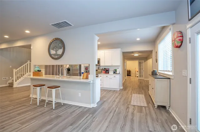 a living room with stainless steel appliances furniture a large window and wooden floor