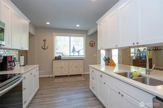 a large white kitchen with stainless steel appliances sink a stove and cabinets