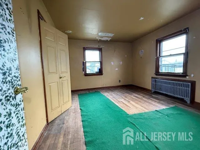 a view of an empty room with window and wooden floor