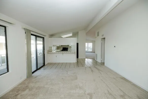 a view of empty room with kitchen and window