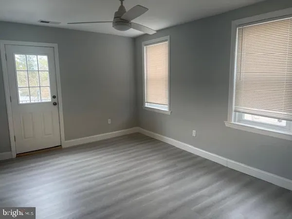 an empty room with wooden floor and windows