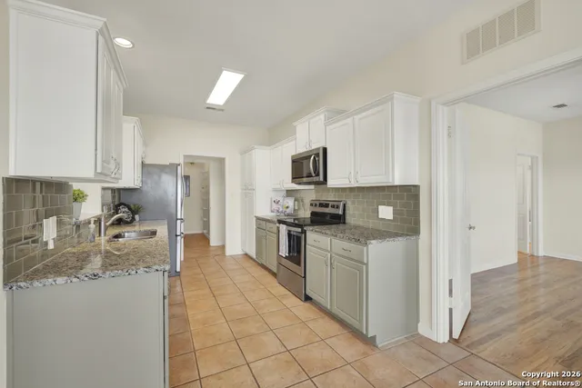 a kitchen with stainless steel appliances granite countertop a sink stove and cabinets