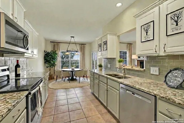 a kitchen with granite countertop a sink a counter top space appliances and cabinets