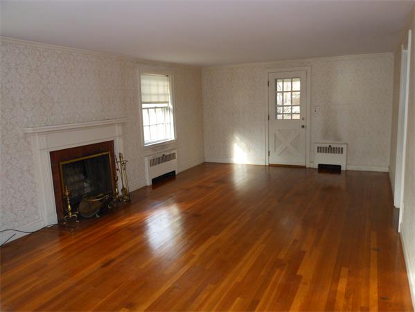 57 Buckingham Road Milton, MA 02186 - Photo 3 of 9 an empty room with wooden floor fireplace and windows
