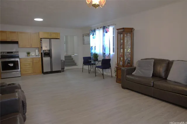 a living room with furniture a refrigerator and kitchen view