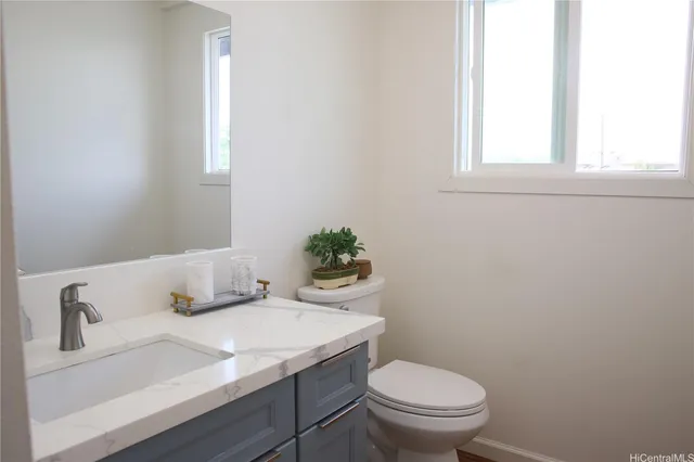 a bathroom with a granite countertop sink and a toilet