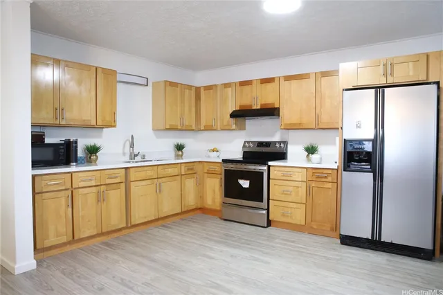 a kitchen with stainless steel appliances granite countertop a refrigerator a stove top oven a sink and dishwasher with wooden floor