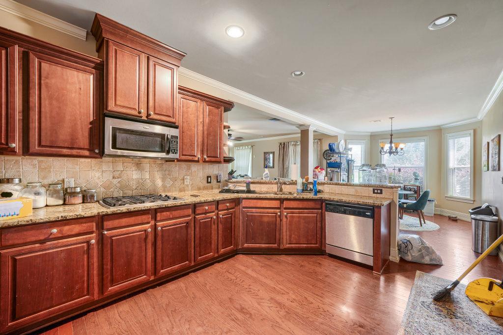 345 Masters Club Boulevard Hampton, GA 30228 - Photo 13 of 30 a kitchen with stainless steel appliances granite countertop wooden cabinets a sink dishwasher a stove and a refrigerator with wooden floor