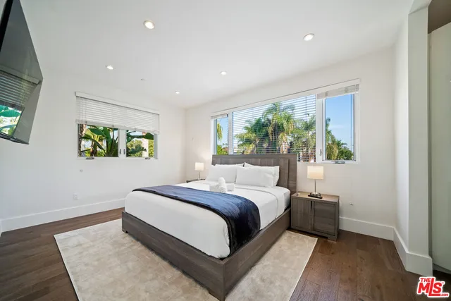 a spacious bedroom with a bed and a flat screen television