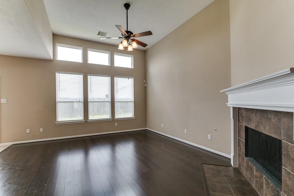 5803 Cedar Field Way Houston, TX 77084 - Photo 11 of 14 an empty room with wooden floor fireplace and windows