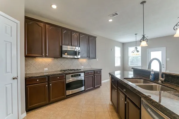 a kitchen with stainless steel appliances granite countertop a sink a stove and a refrigerator