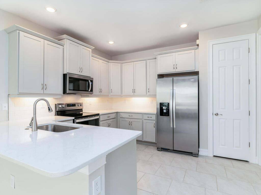 1176 Enbrook Loop Naples, FL 34114 - Photo 4 of 35 a kitchen with granite countertop a refrigerator a sink a stove a microwave and cabinets